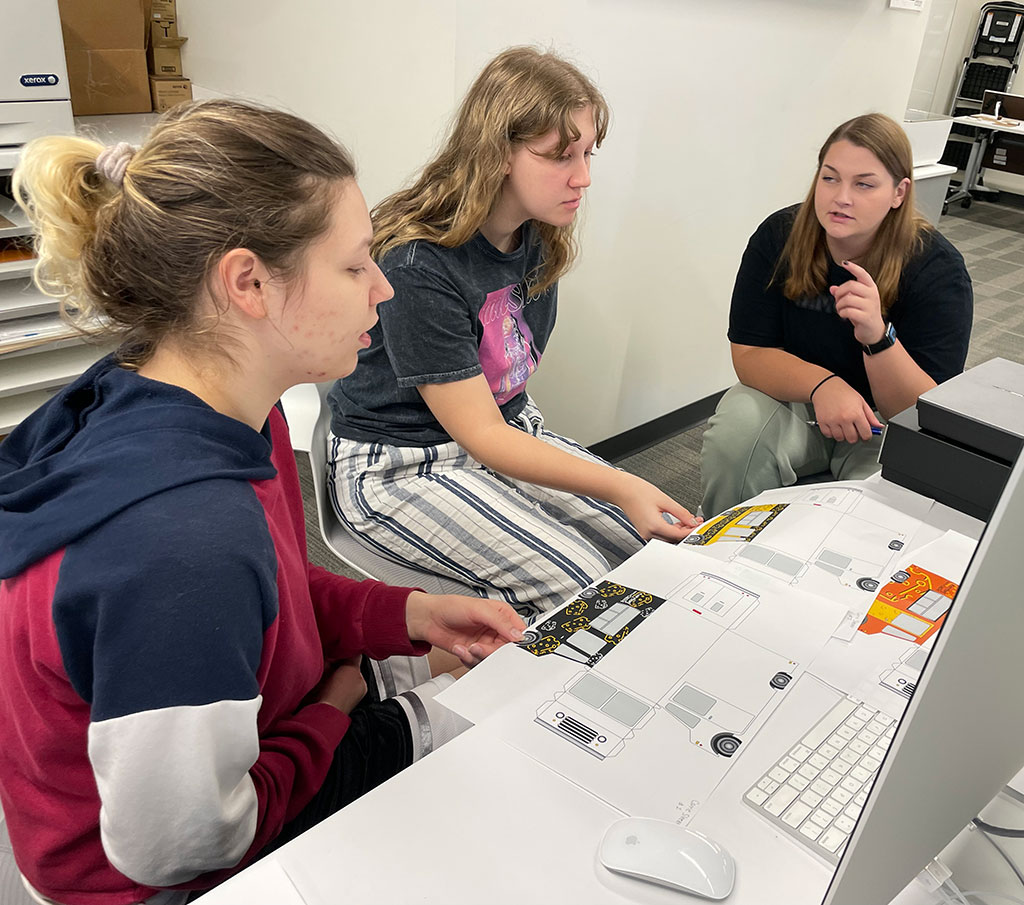 Graphic design students in a group discussion about food truck designs.